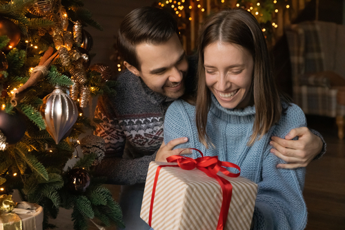 A couple smiling over a wrapped gift box