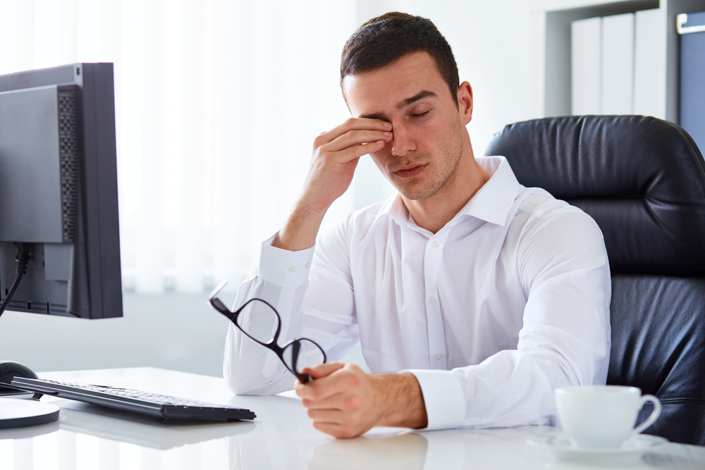 Man rubbing his eyes at work