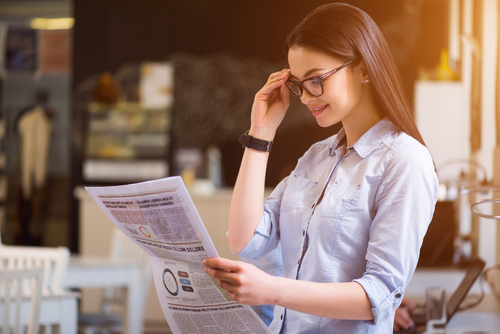 Young woman in glasses reading paper