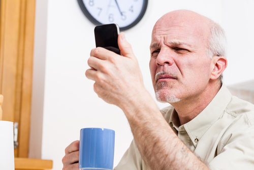 Senior man reading phone and squinting