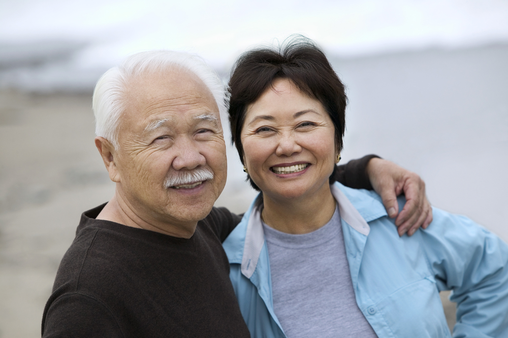 husband and wife posing for picture at the beach